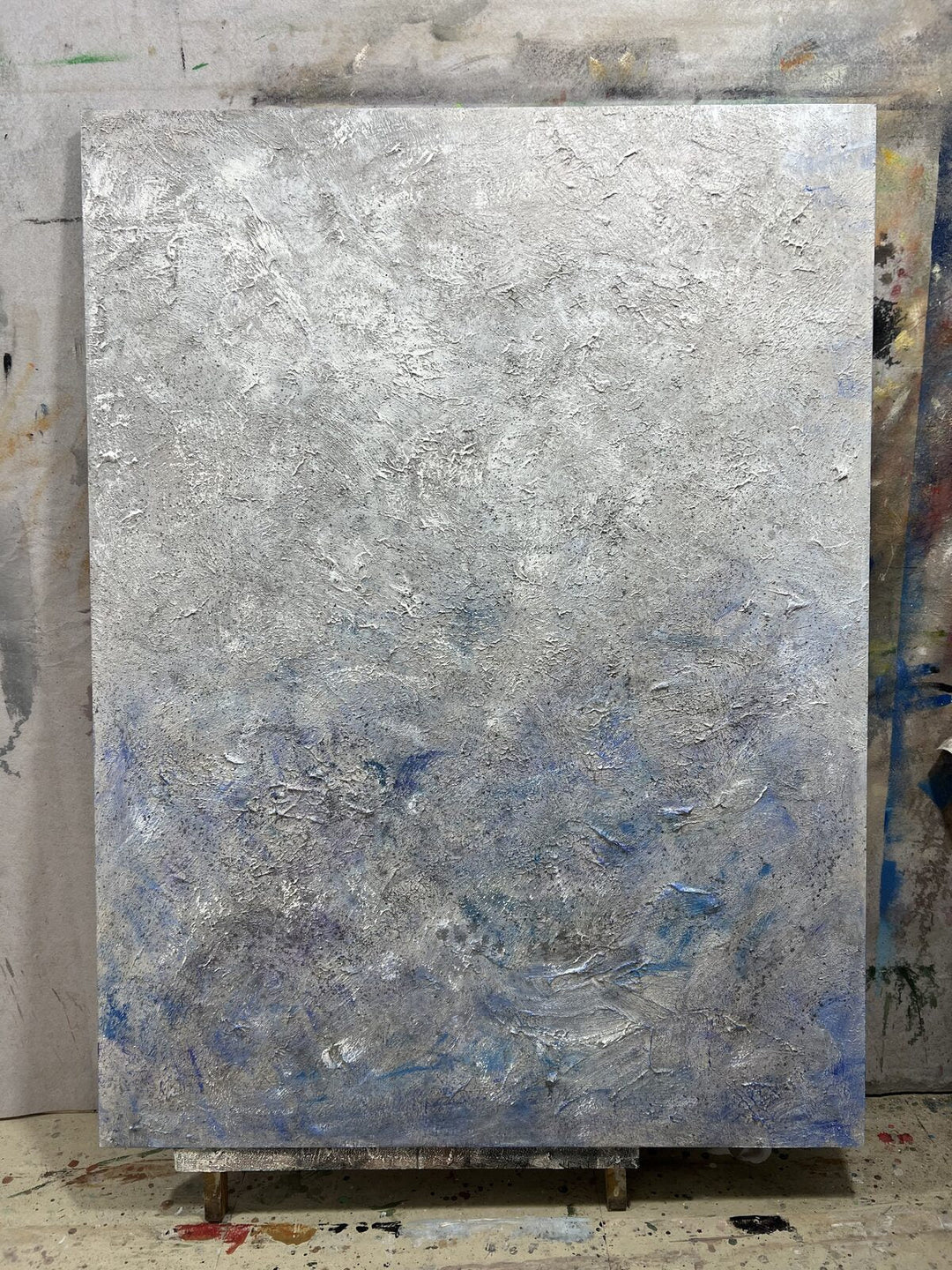 Hand-painted silver-blue textured abstract wall art that pairs with a gray sofa