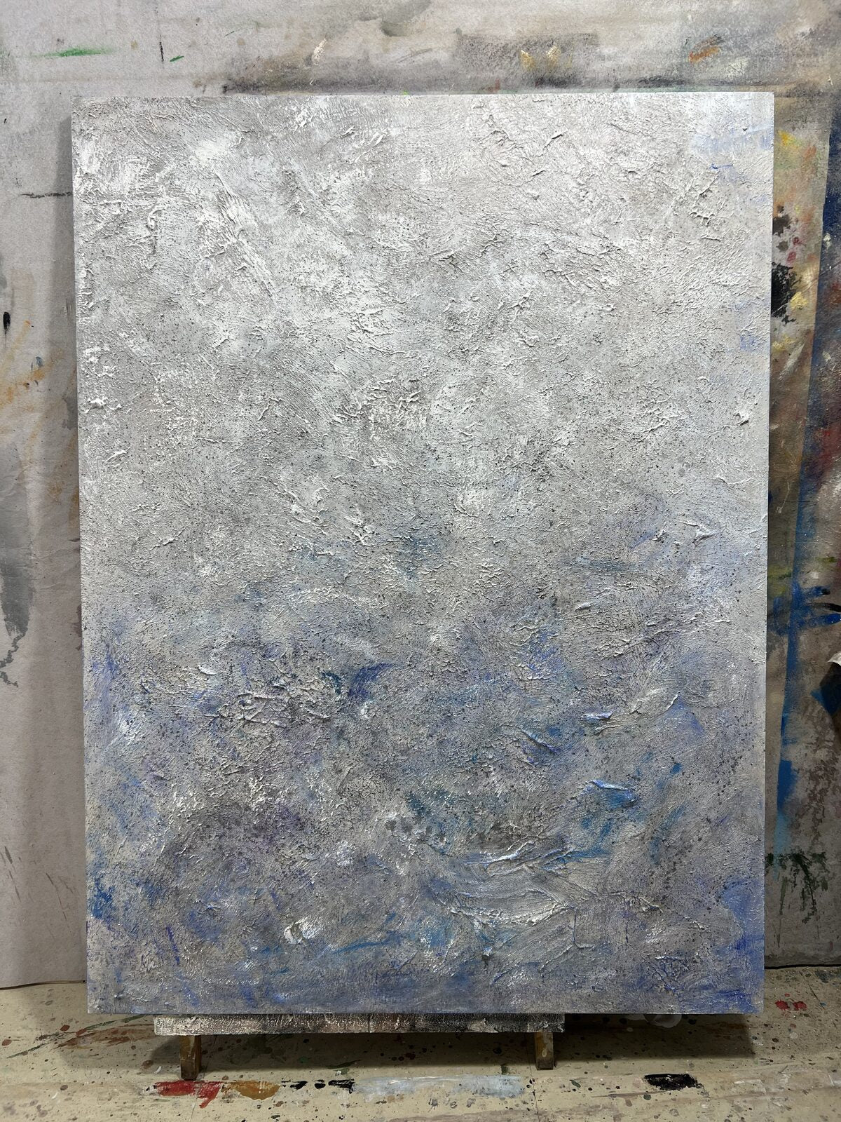 Hand-painted silver-blue textured abstract wall art that pairs with a gray sofa