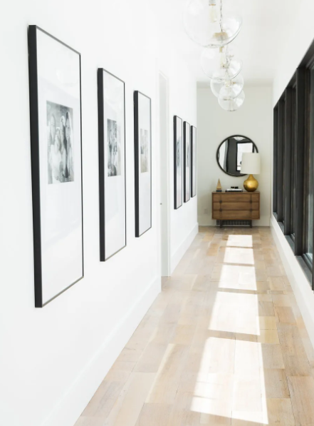 Three framed abstract paintings arranged in a single row along one wall of a narrow hallway.